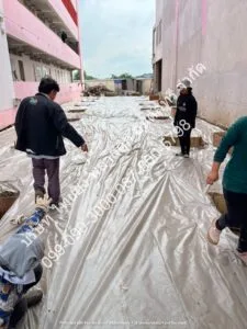 ผู้คุมงานกำลังตรวจงานติดตั้งพลาสติกปูพื้นก่อนเทคอนกรีต เพื่อเตรียมการวางตะแกรงเหล็กในขั้นตอนต่อไป