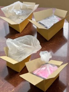 กล่องกระดาษเปิดสี่ใบ วางอยู่บนโต๊ะหินอ่อนสีน้ำตาลแดง โดยในกล่องบรรจุถุงพลาสติกใส 